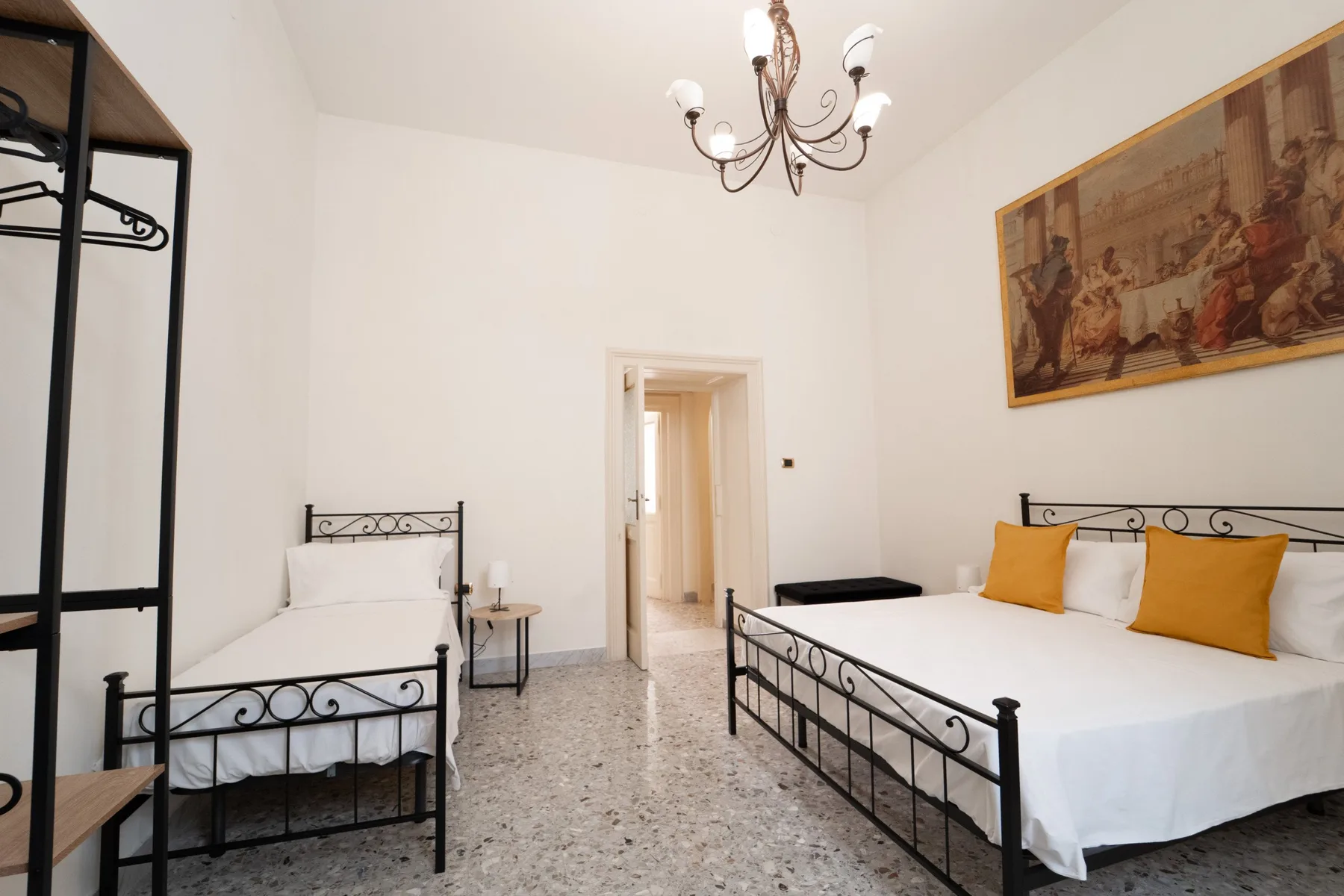 A bedroom with two beds, black metal frames, and white bedding.
