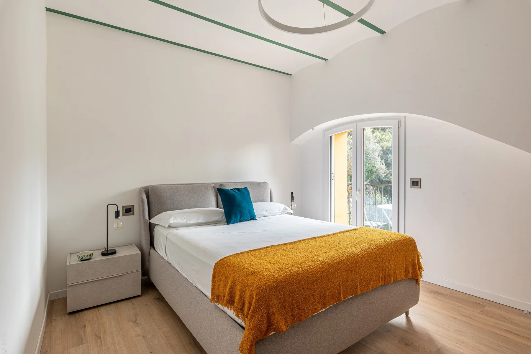 Un dormitorio luminoso con una cama arreglada y una colcha color mostaza.