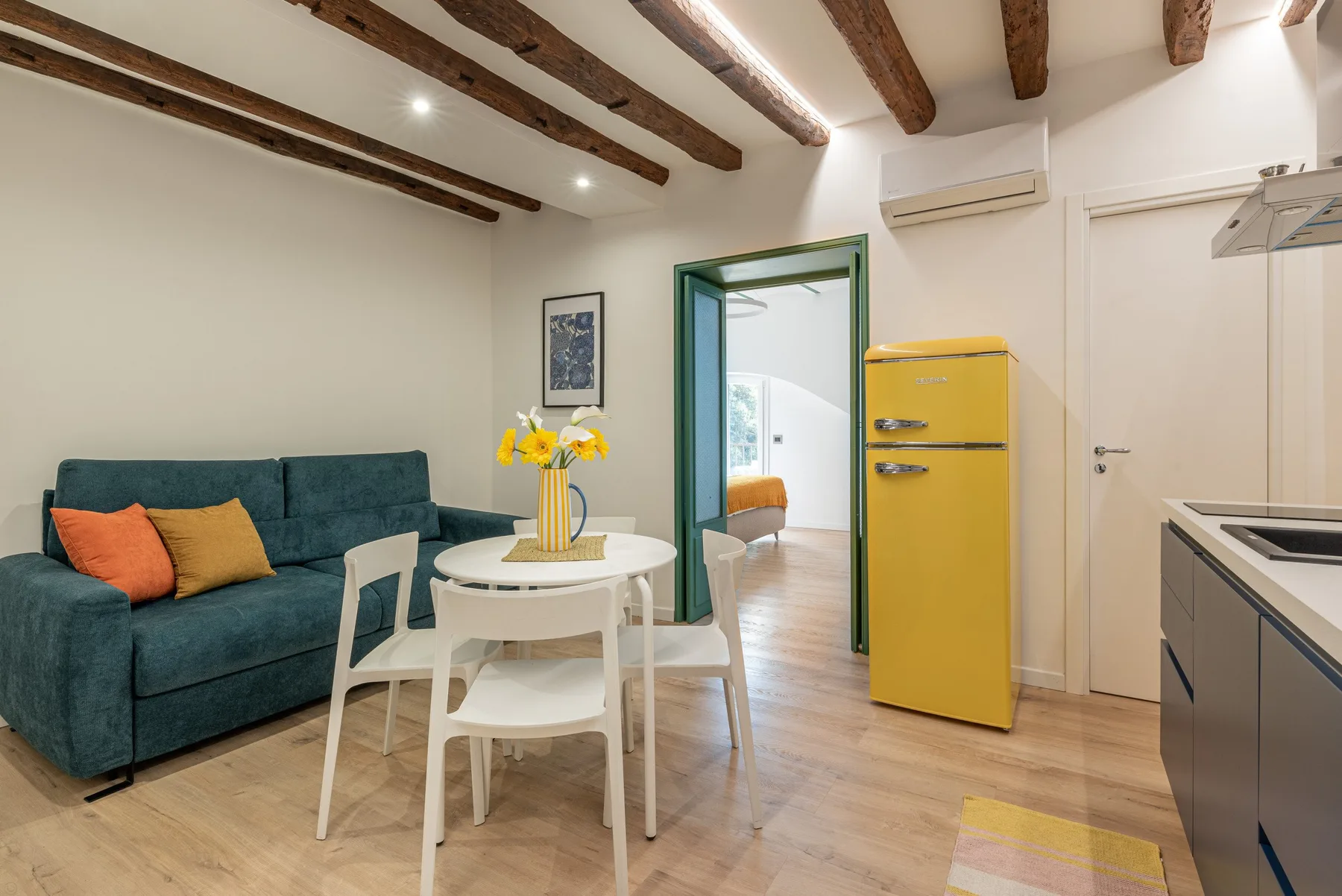 Una luminosa sala de estar y comedor con asientos color turquesa y una mesa redonda.