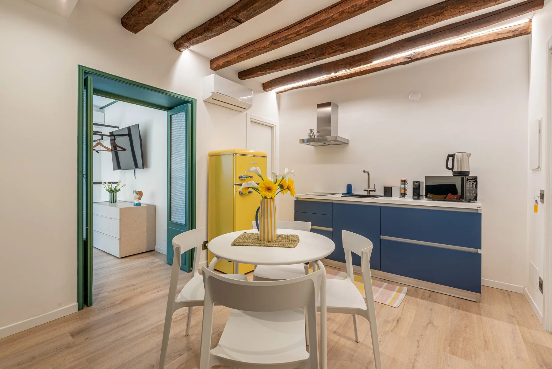 Un comedor con una mesa redonda está junto a una encimera azul de cocina.