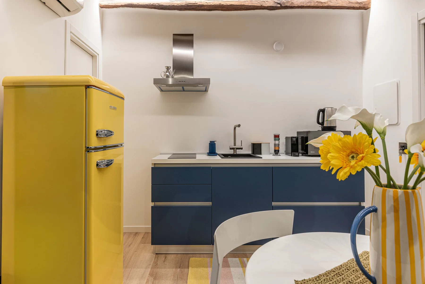 Una cocina moderna con gabinetes azul oscuro y un refrigerador amarillo.