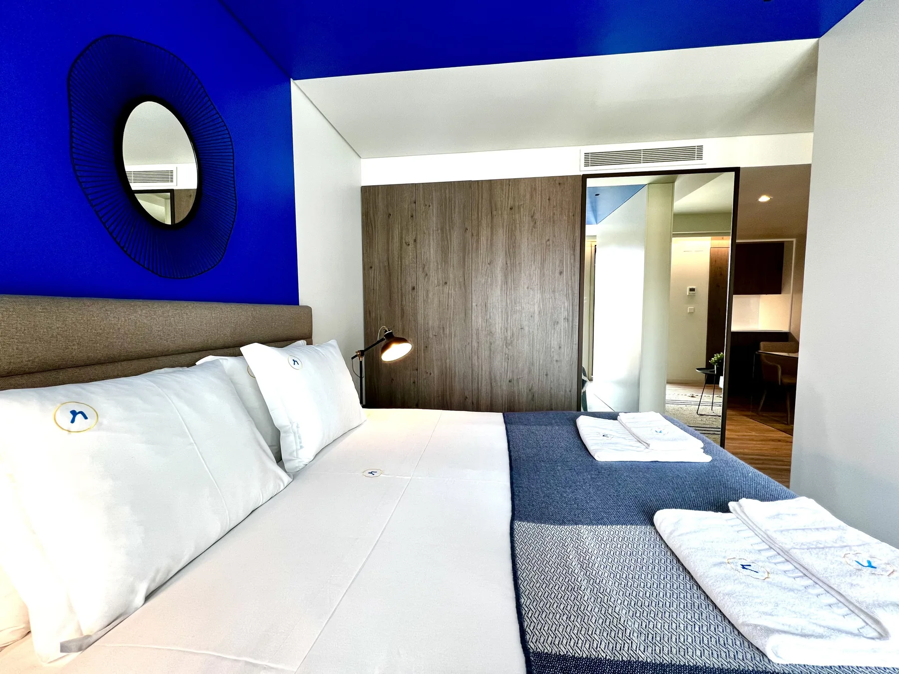 Un dormitorio con una cama grande, una pared azul y puertas de armario con espejo.