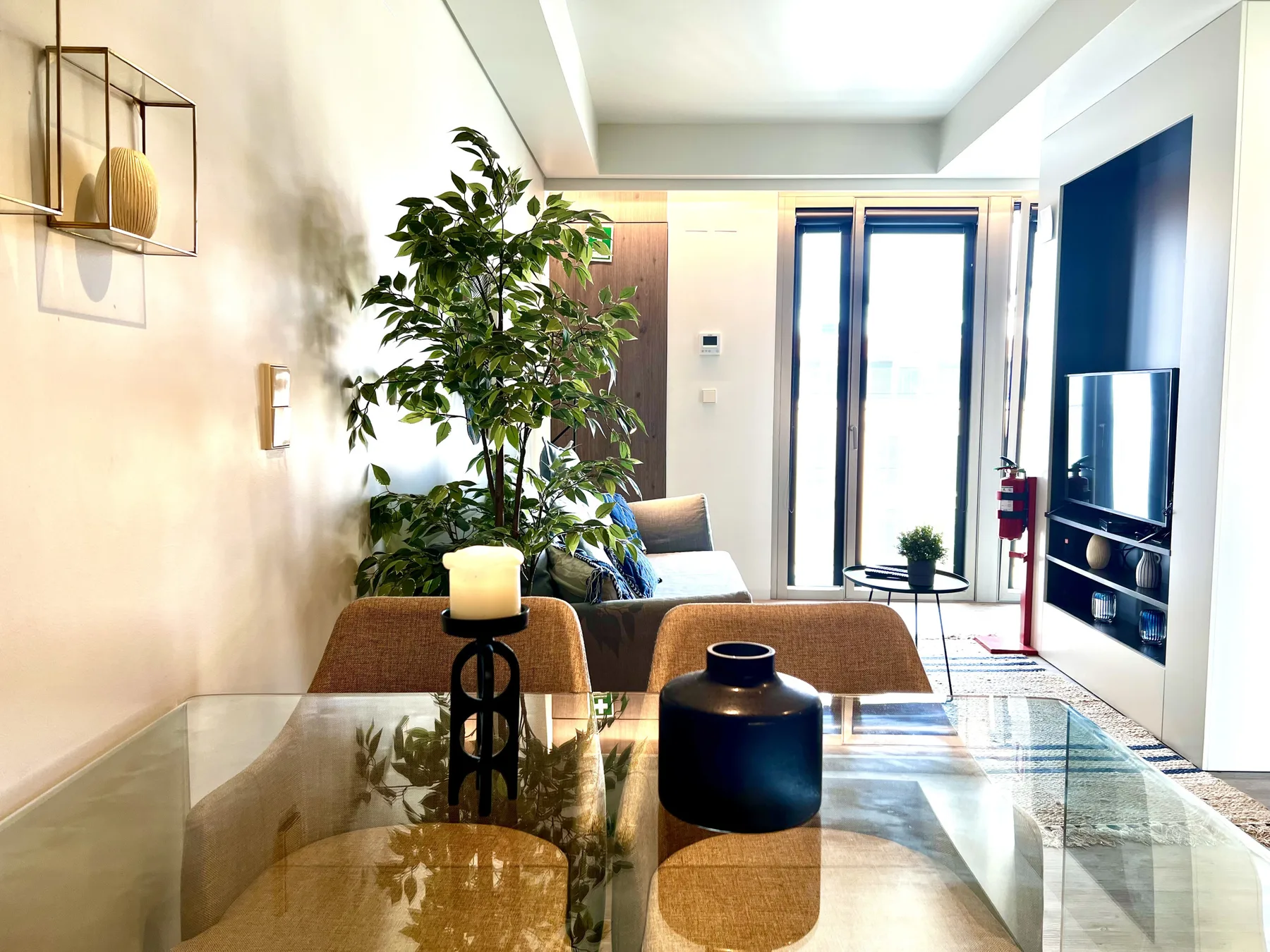 A bright living room with seating, a glass coffee table, and a television.