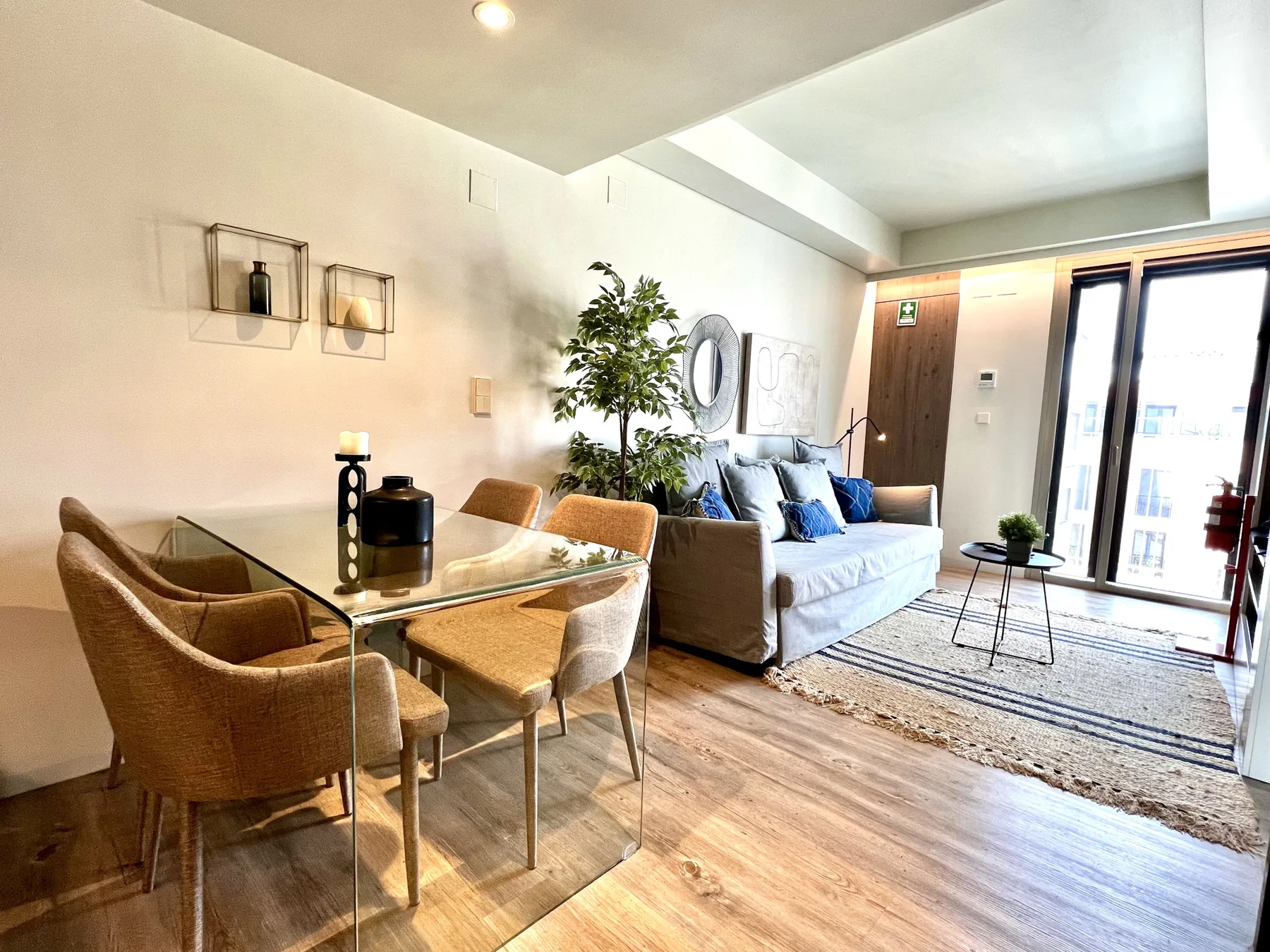Una luminosa sala de estar y comedor con asientos, una mesa y grandes ventanas.