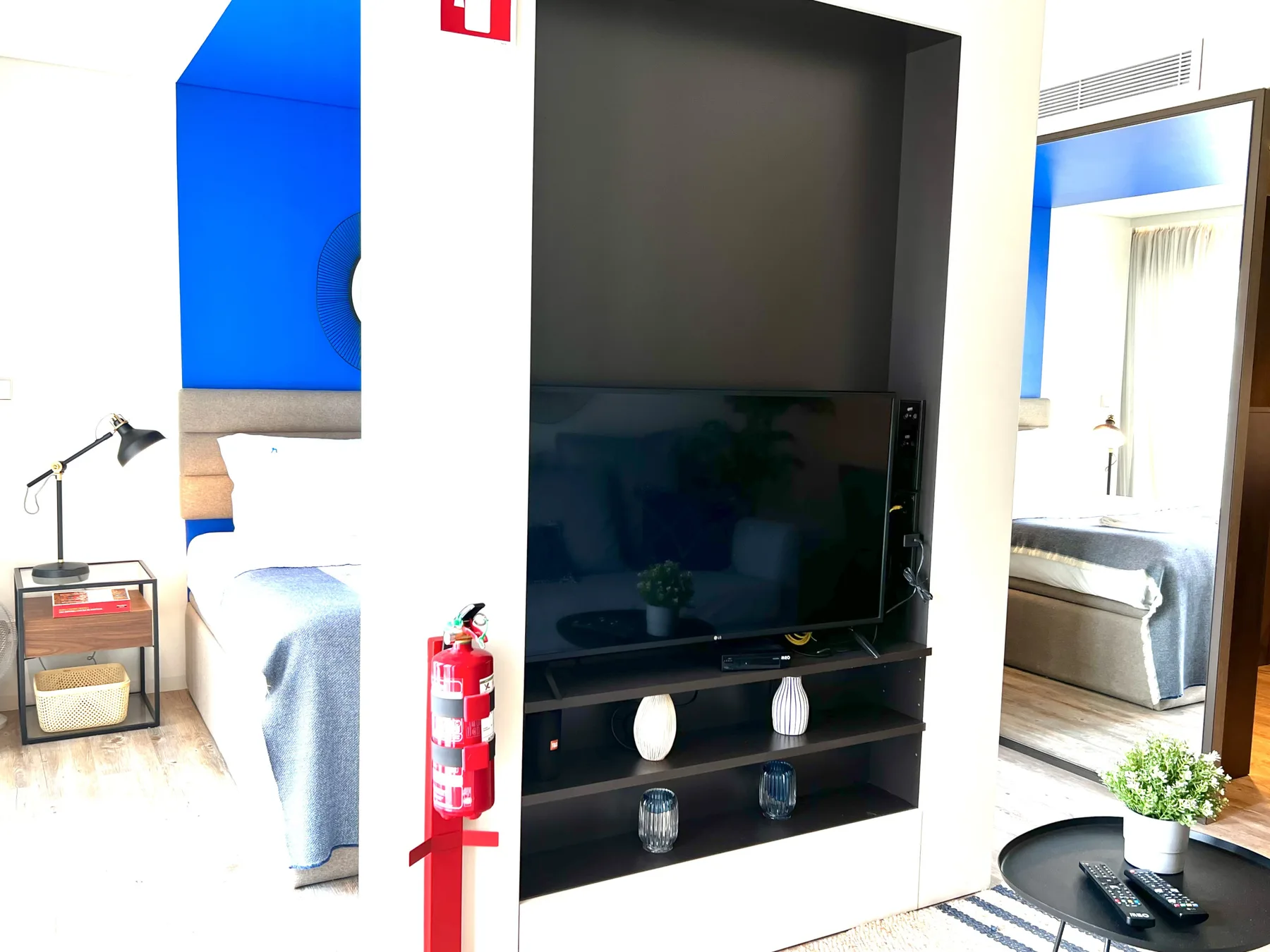 A bedroom with a television set in a dark built-in shelving unit.