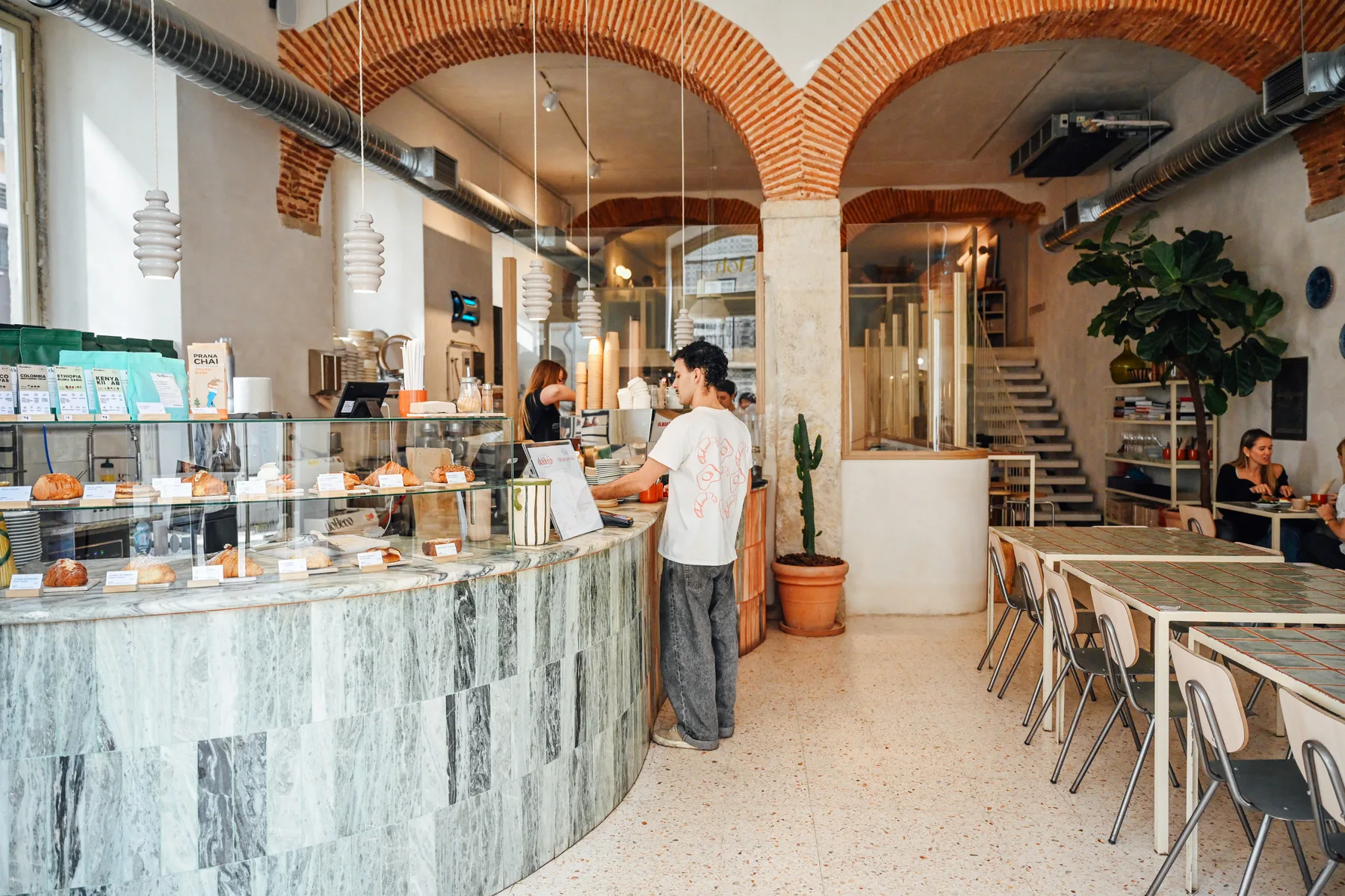Una barra de café y una zona de comedor están bajo arcos de ladrillo visto.
