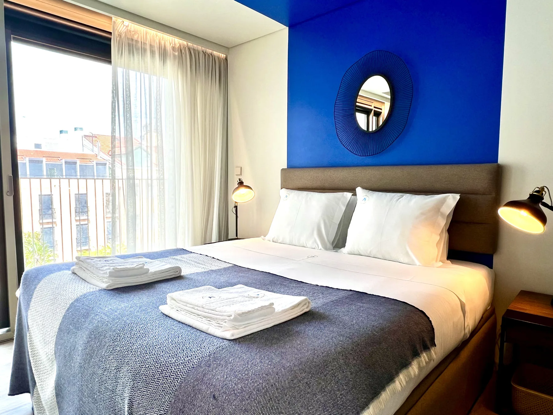 Dormitorio con una cama ordenada y una pared decorativa azul intenso.