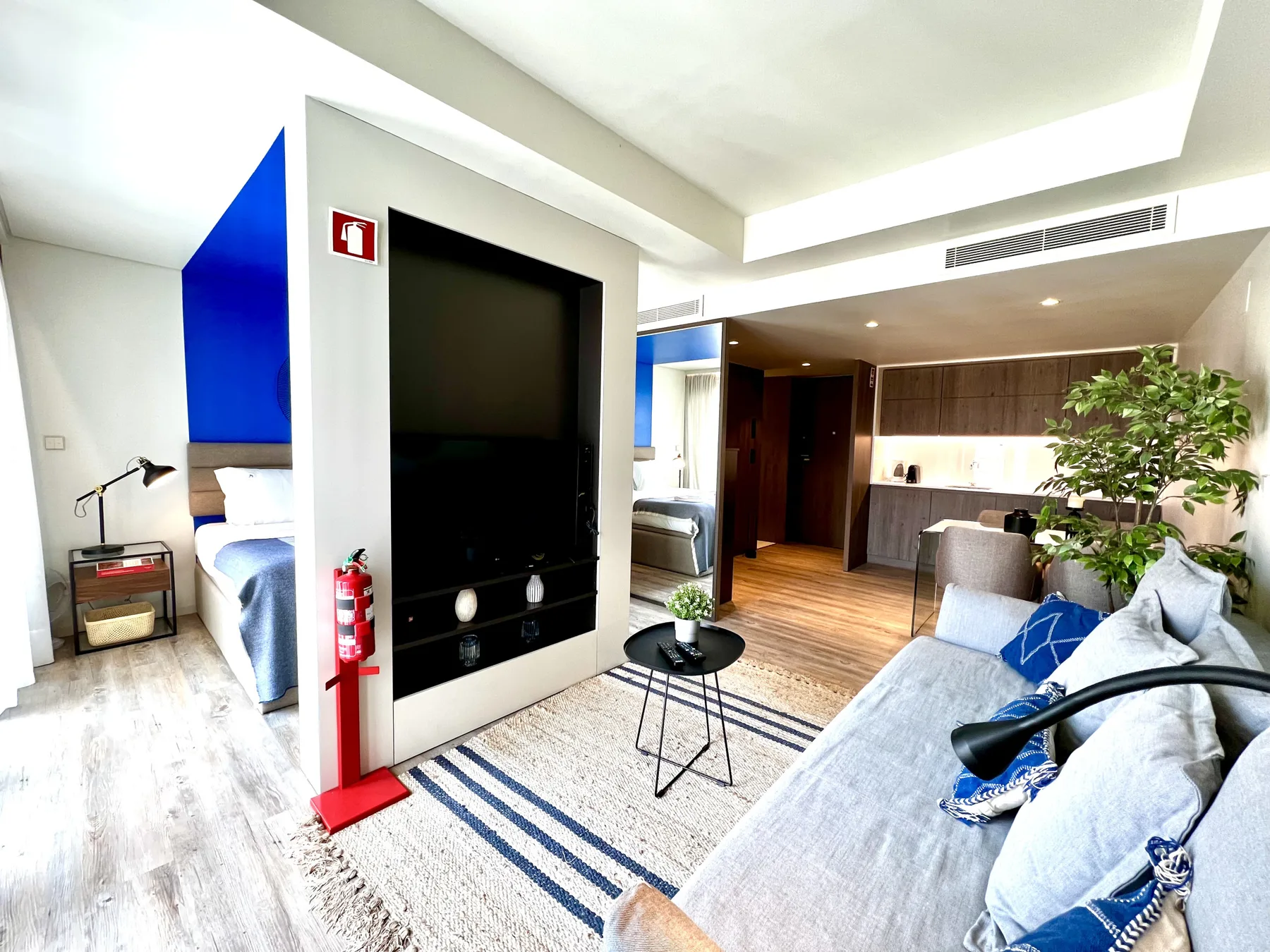 Una luminosa sala de estar con asientos, un televisor y vista al dormitorio.