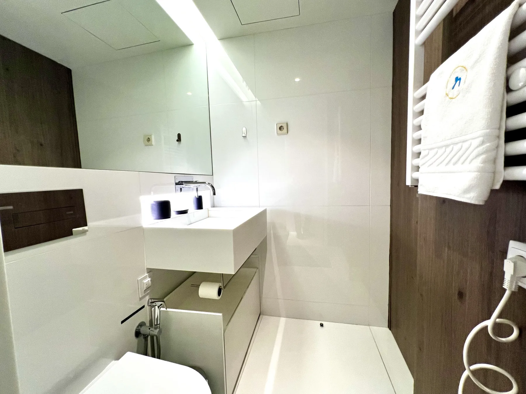 Un baño luminoso con lavabo suspendido y zona de ducha.