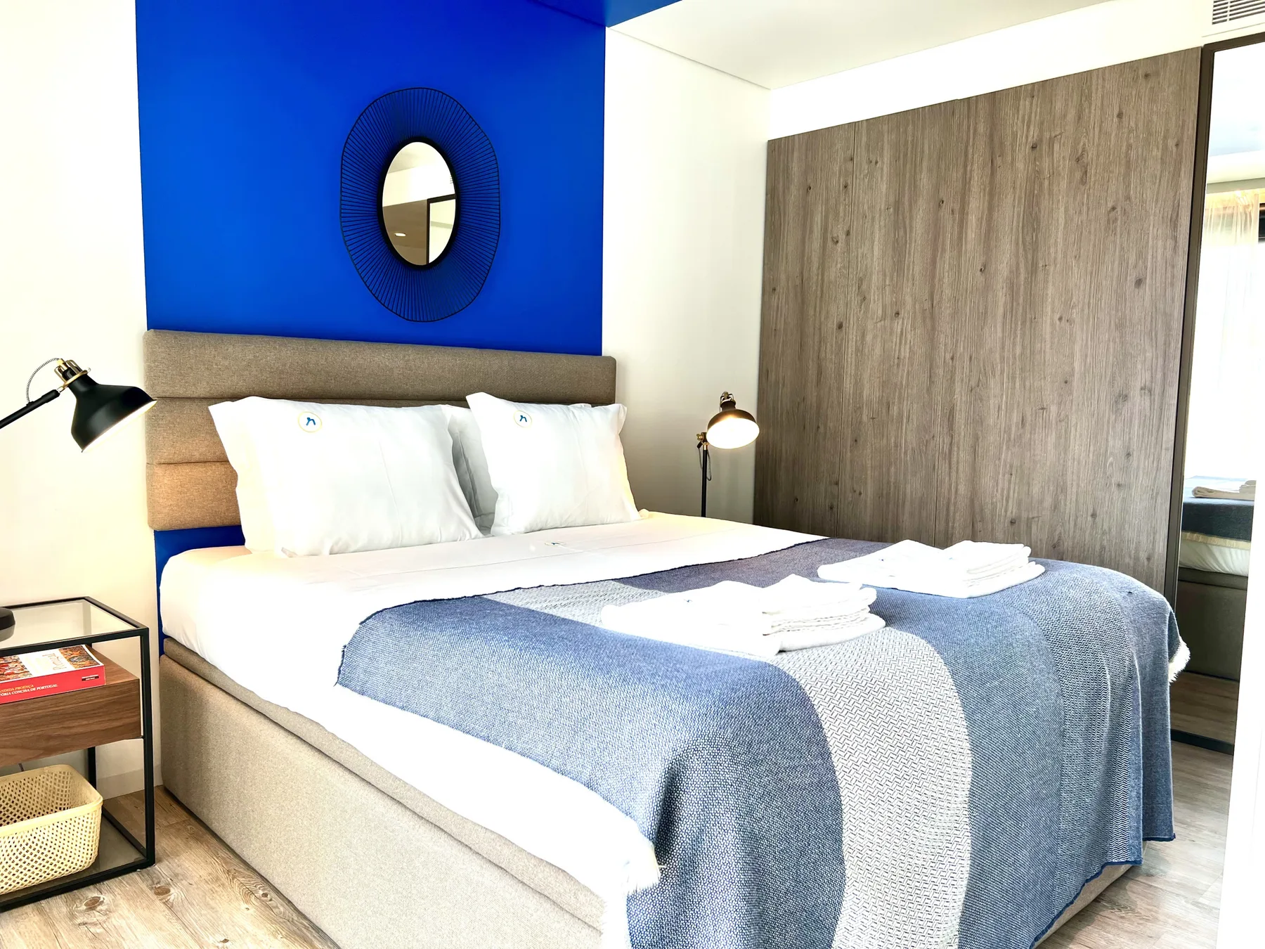 A bedroom with a neatly made bed and a blue accent wall.