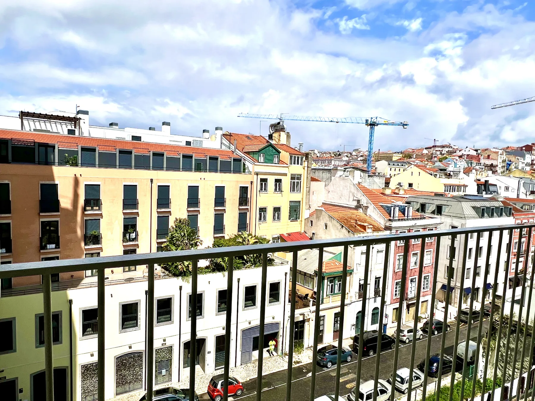 Una calle urbana y edificios muy próximos se ven detrás de una barandilla de balcón.