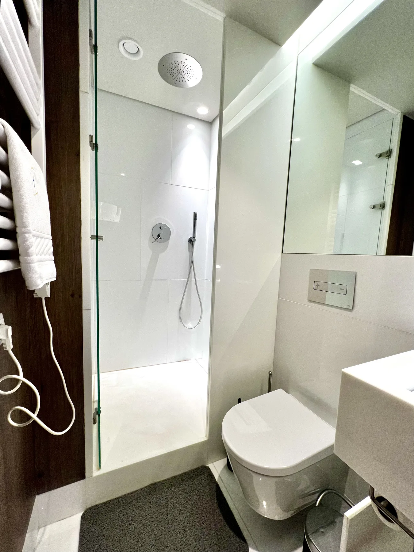 Un baño luminoso y moderno con ducha de cristal, inodoro y espejo en la pared.