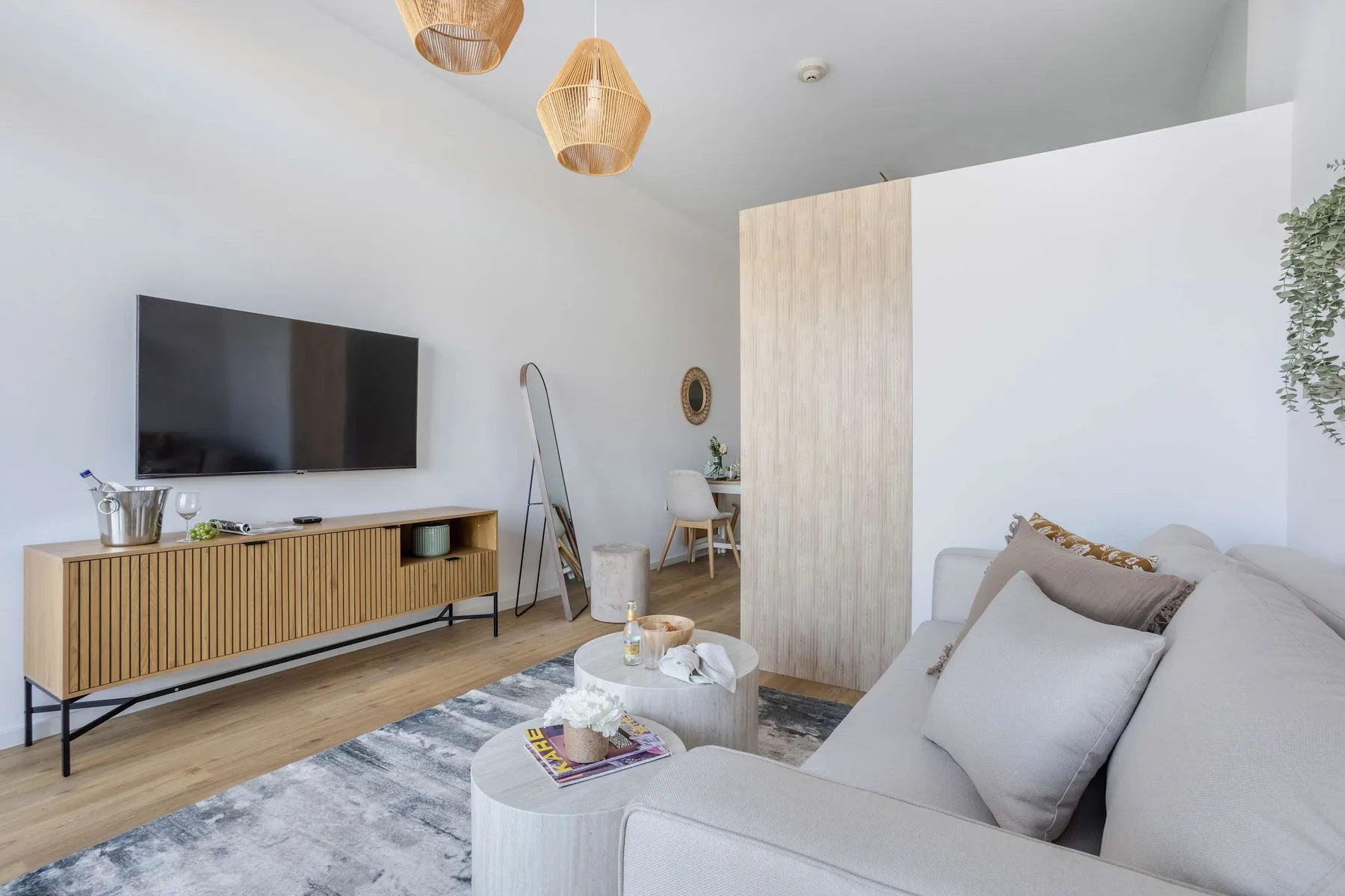 A bright living room with seating, a television, and a small dining area.
