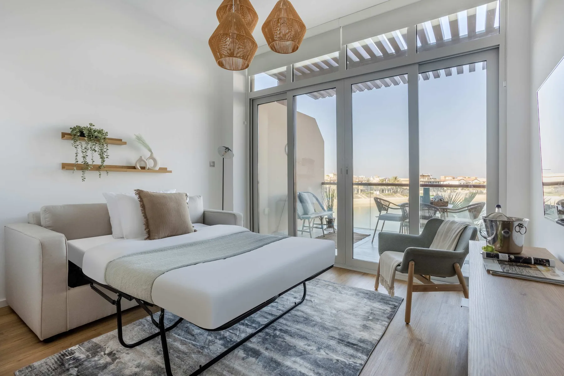 A bright living area with a daybed, seating, and glass doors opening onto a balcony.