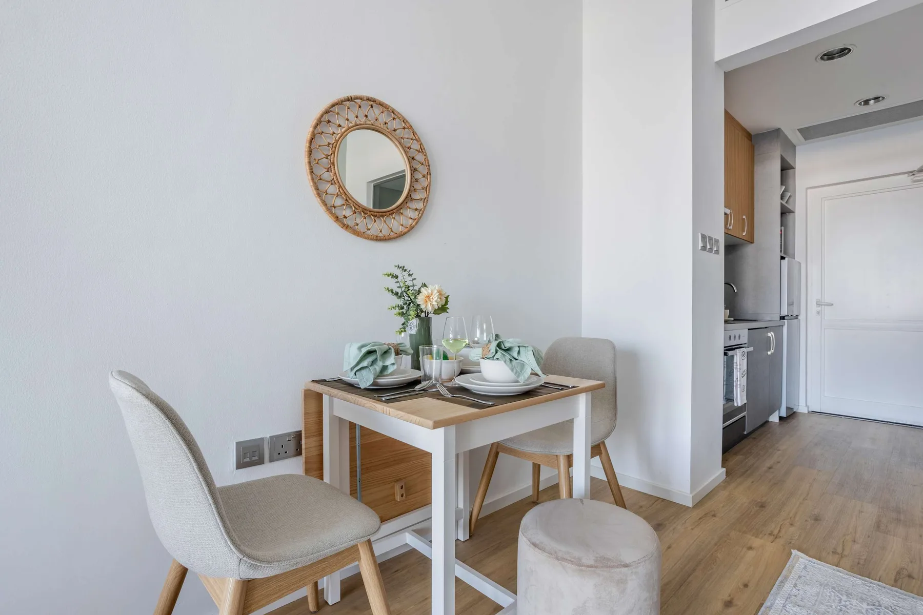 A dining area with a set table, chairs, and an adjacent kitchen.
