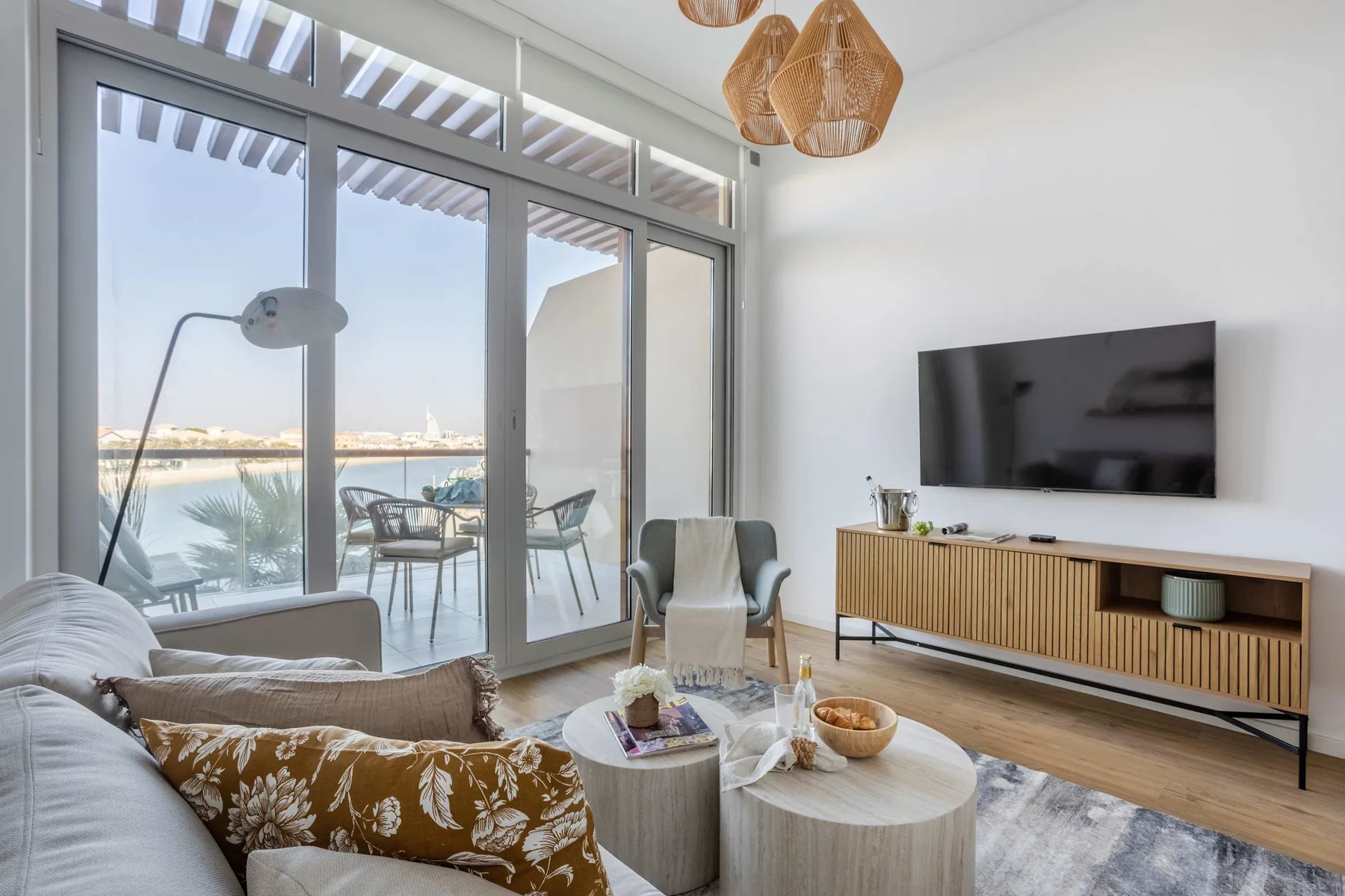 A bright living room with seating beside large windows overlooking the water.