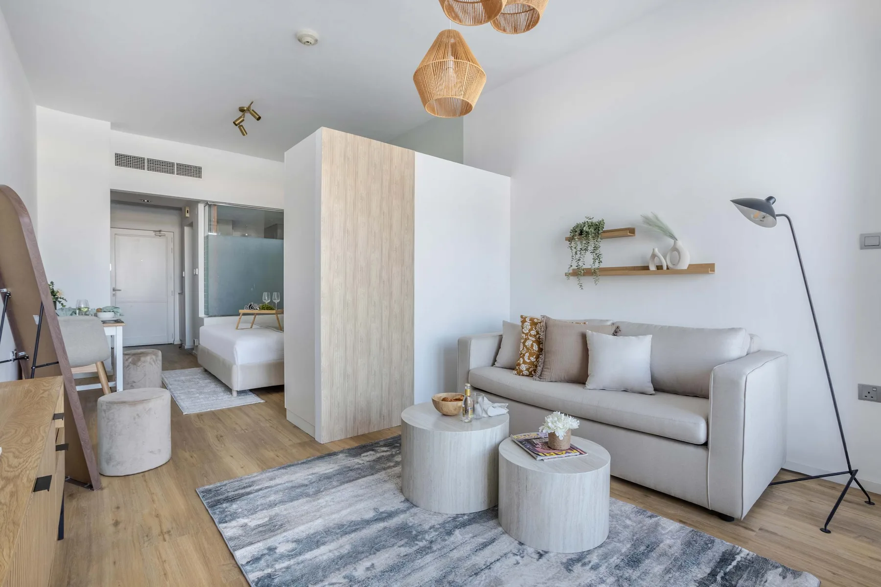 A bright living area with a sofa, low tables, and a floor lamp.