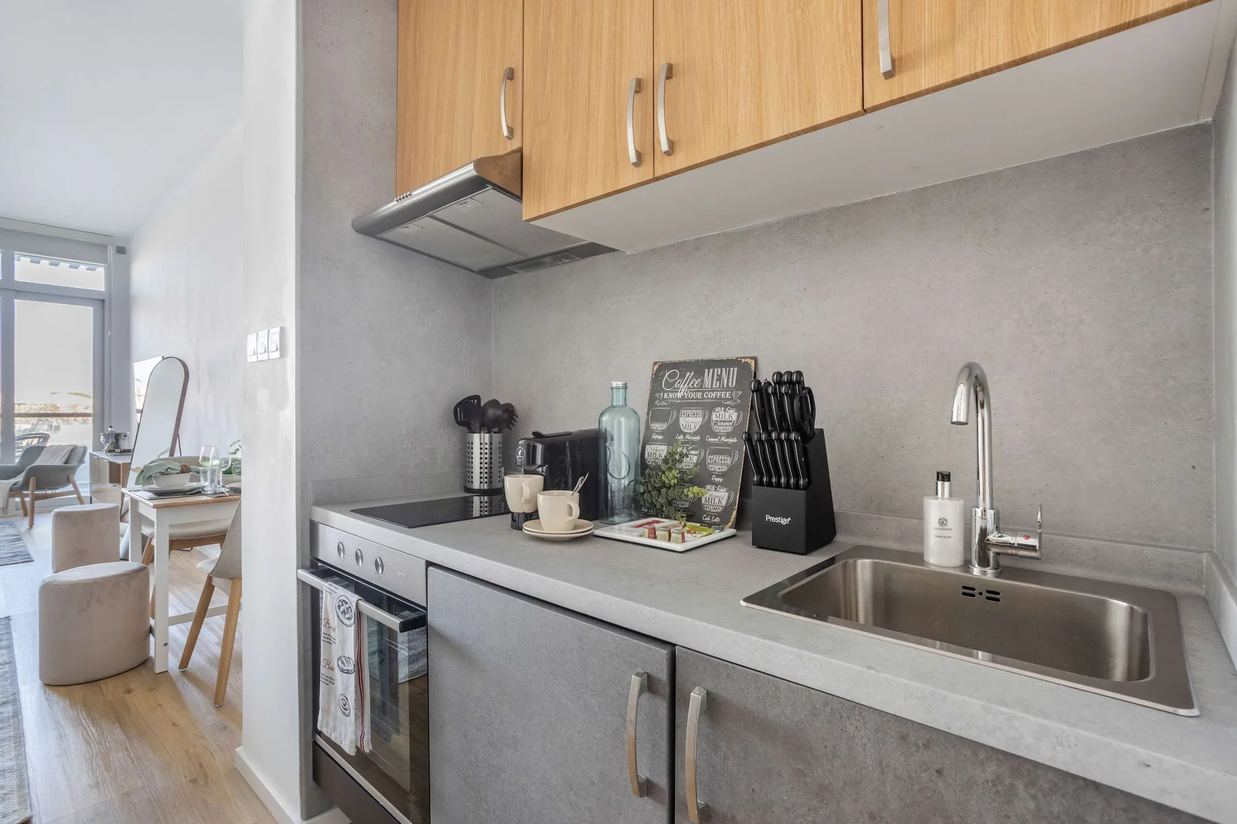 A compact kitchen with wooden cabinets, a countertop, and a stainless-steel sink.