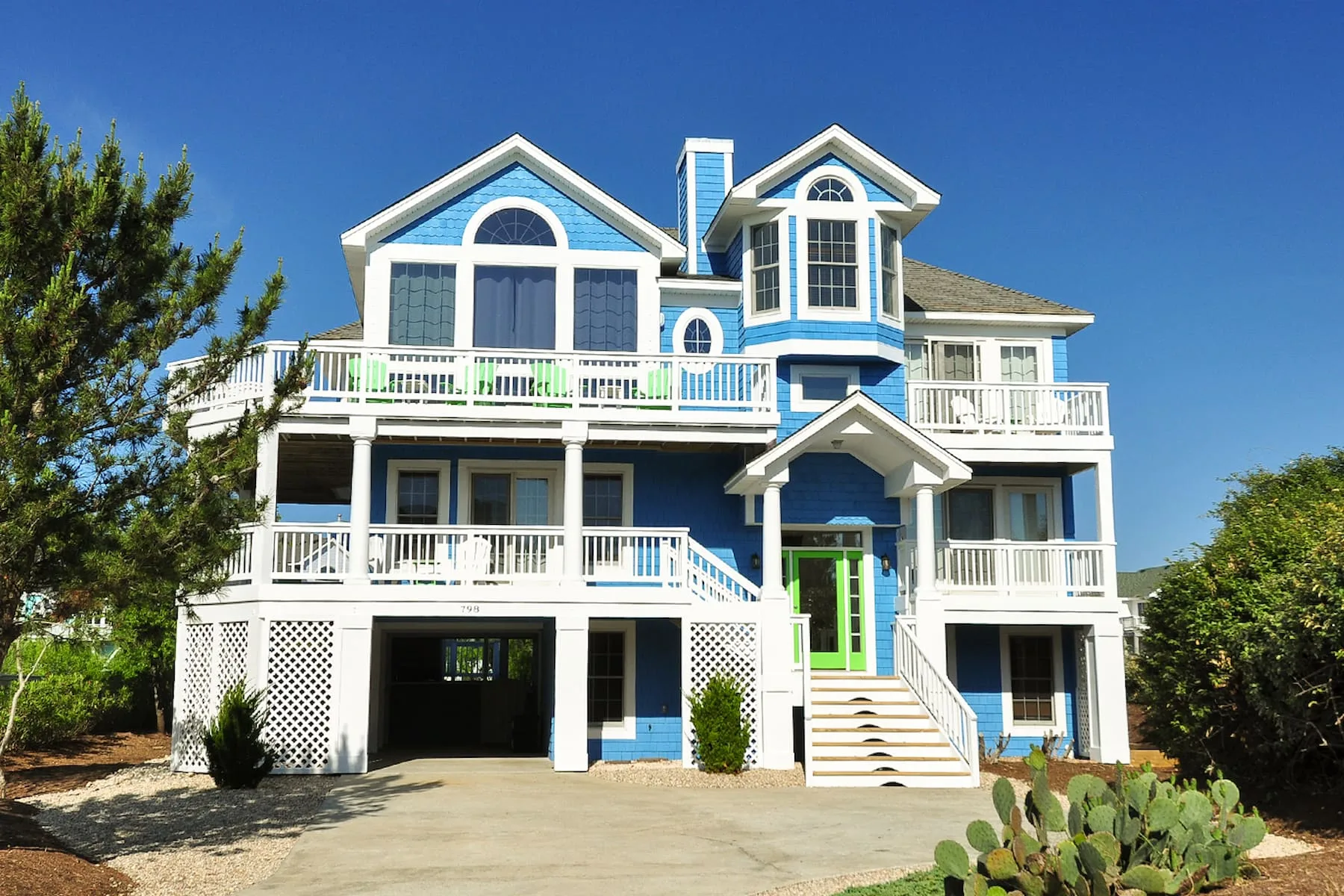 A large multi-level house with white balconies and blue trim.