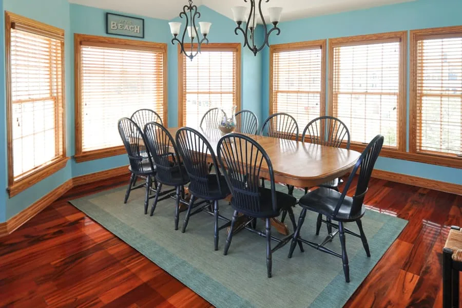 Comedor con una mesa larga de madera y sillas junto a grandes ventanas.