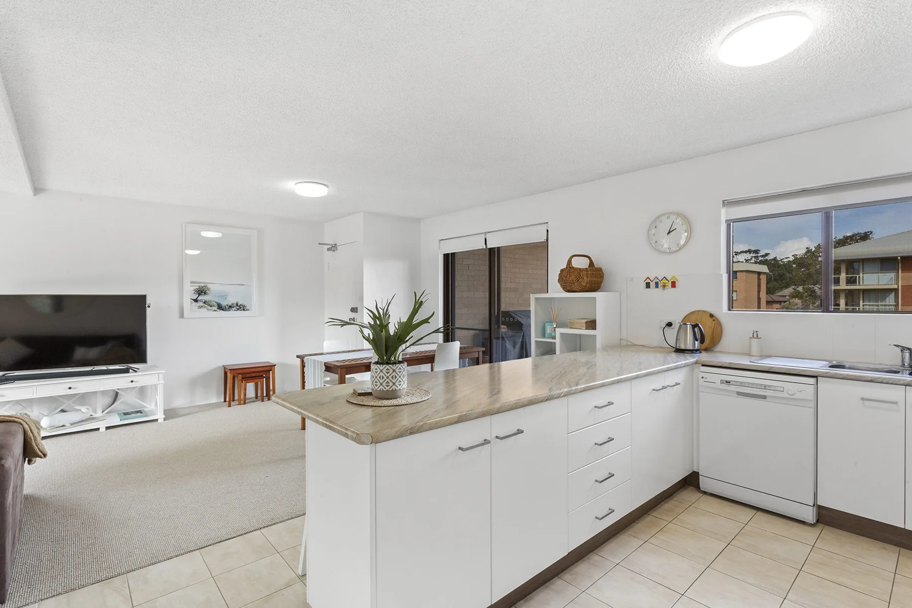 Una cocina luminosa con una isla central y una sala de estar contigua.