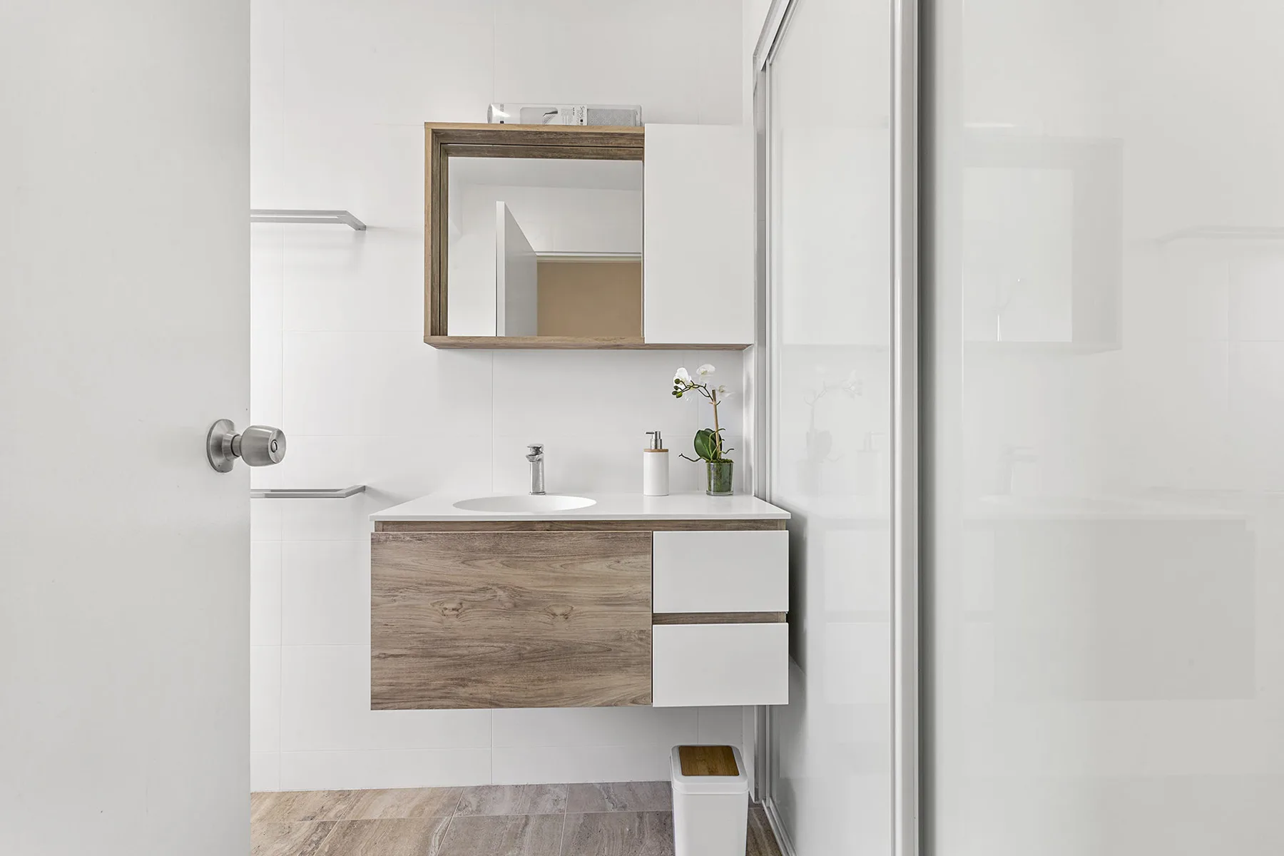 Un baño luminoso con tocador, espejo y ducha de vidrio.