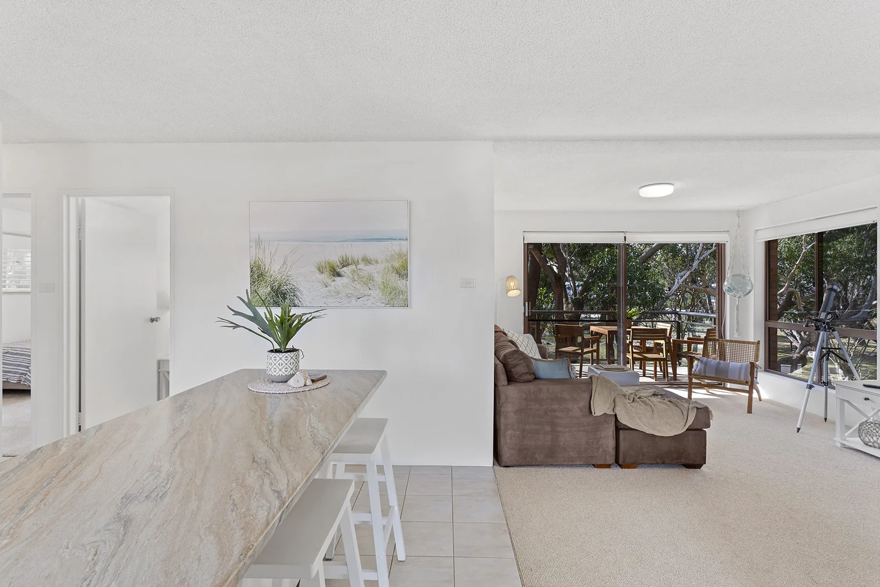 Un comedor y sala de estar de concepto abierto con grandes ventanas y vistas a los árboles.