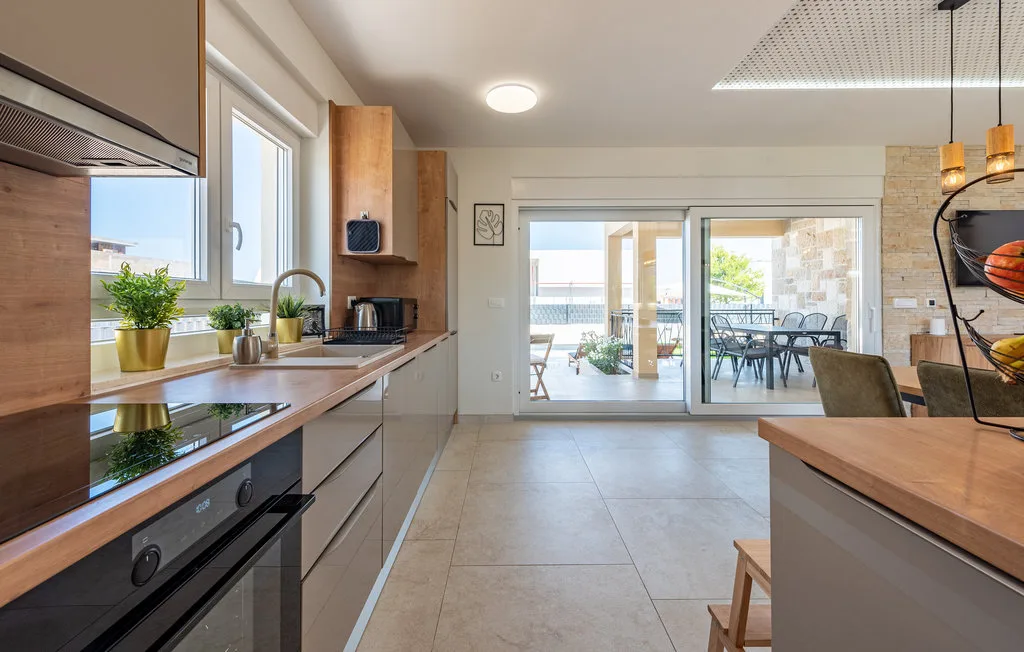 A bright kitchen opens onto a dining area through wide glass doors.