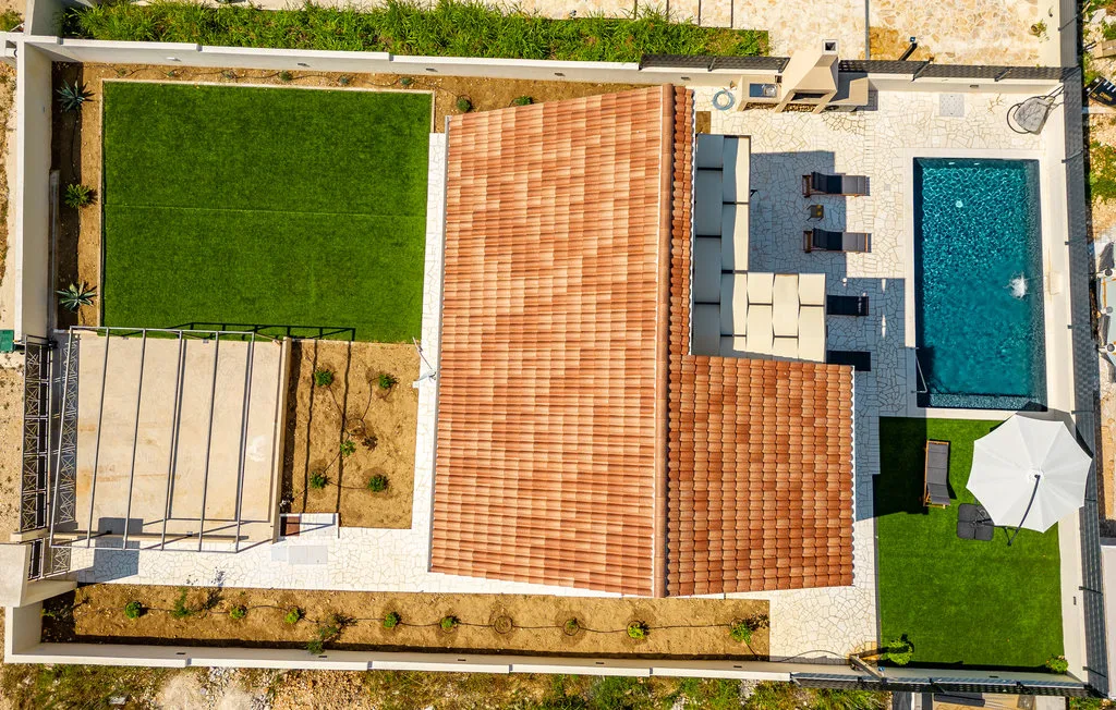 An aerial view shows a house, swimming pool, and landscaped outdoor areas.