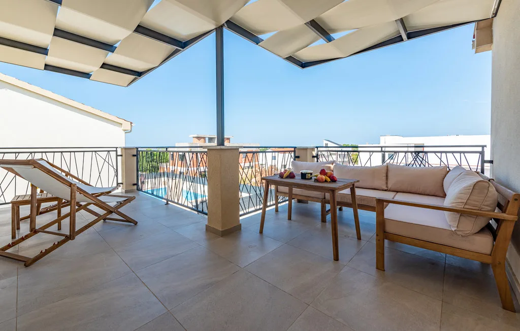 A covered terrace with outdoor seating and a table overlooking the sea.