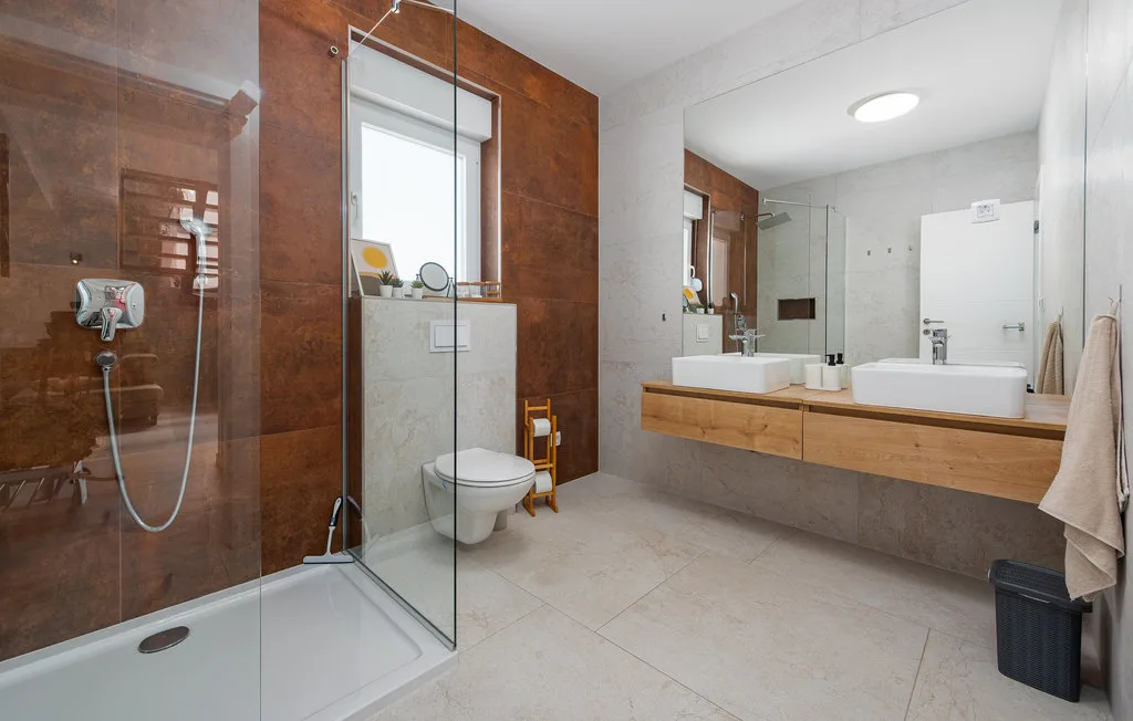 A modern bathroom with a glass shower, wall-mounted sinks, and a toilet.