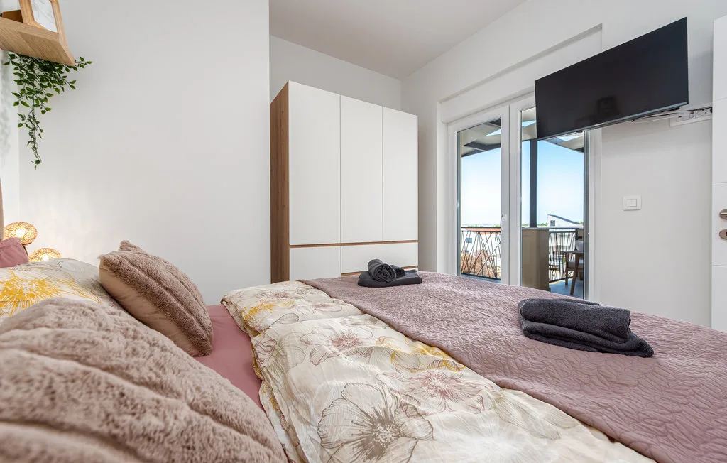 A bedroom with a bed, wardrobe, and glass doors opening onto a balcony.