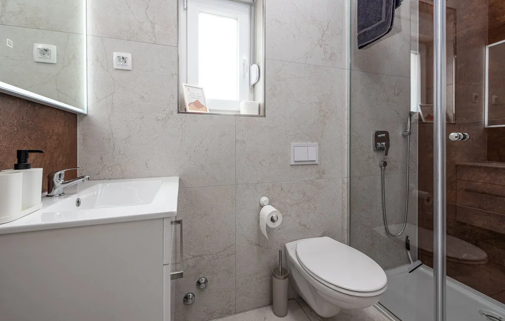 A tiled bathroom with a sink, toilet, and glass shower.