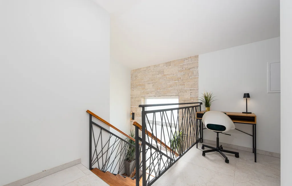 A bright landing overlooks a staircase, with a desk and chair nearby.