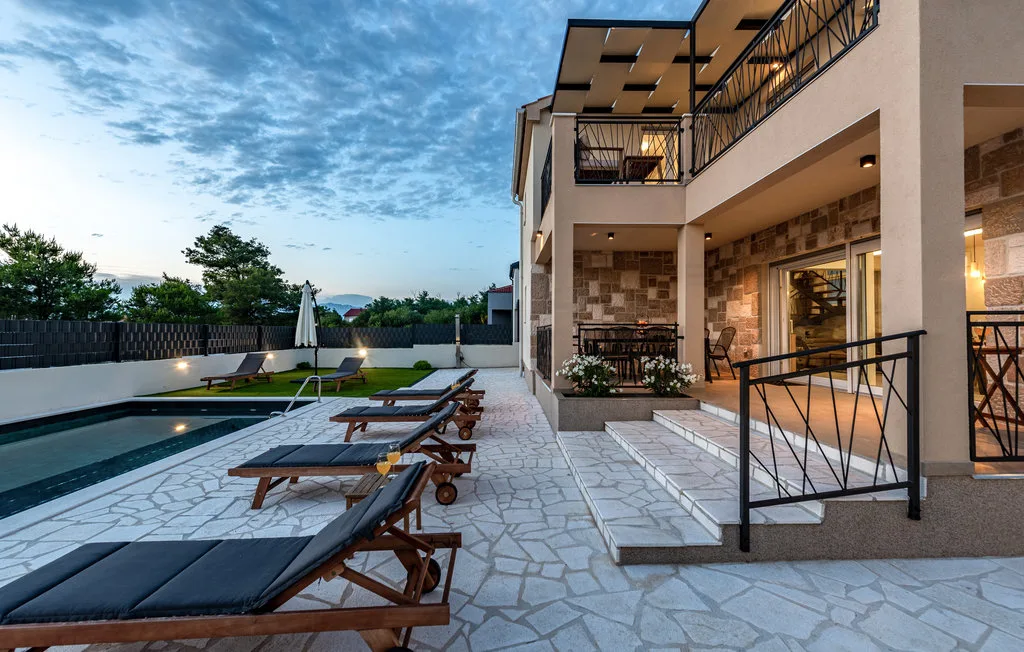 An outdoor poolside patio with lounge seating beside a modern building.