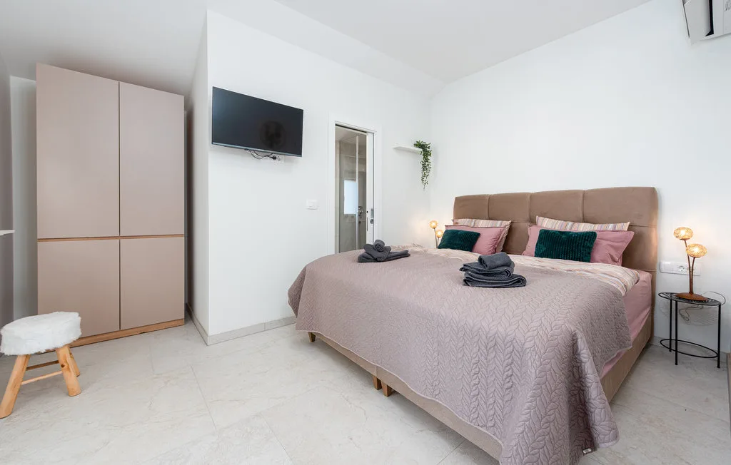 A bedroom with a large bed, wall-mounted television, and wardrobe.