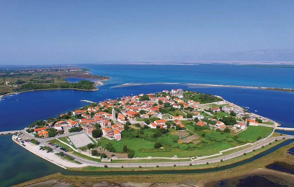 An aerial view of a coastal town surrounded by blue water and green fields.