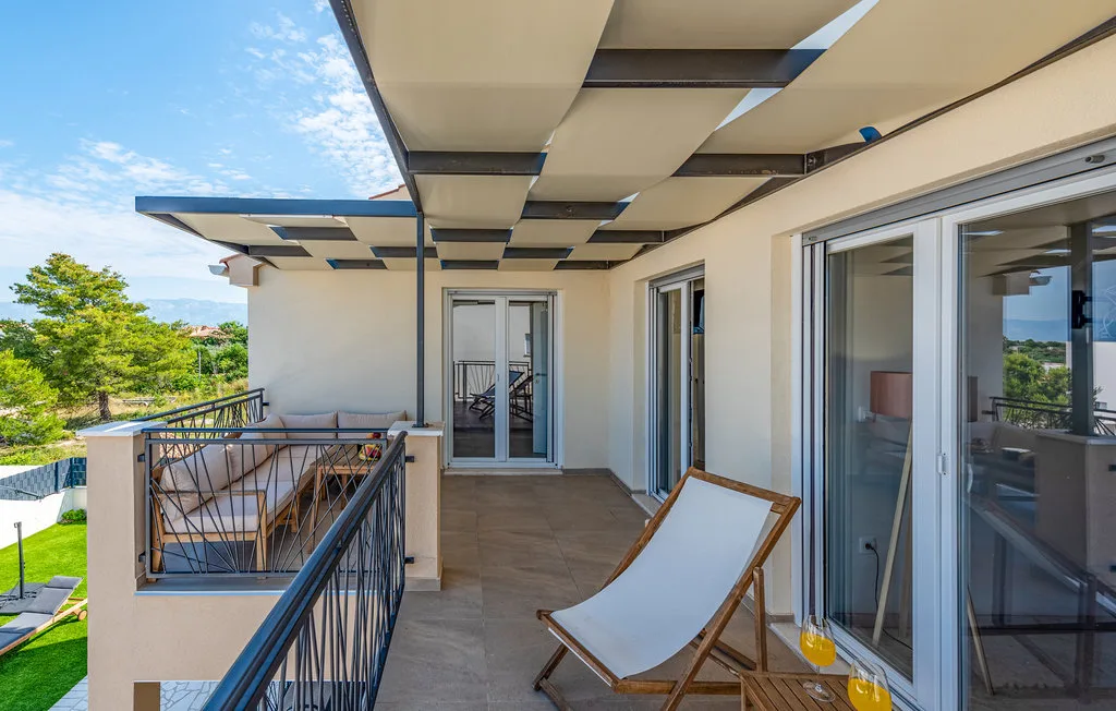 A covered outdoor terrace with lounge seating and glass doors.