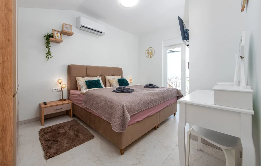 A bright bedroom with a large bed, bedside table, and a small desk.