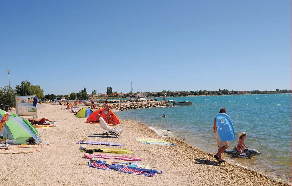 A sunny beach with colorful umbrellas and people beside the water.