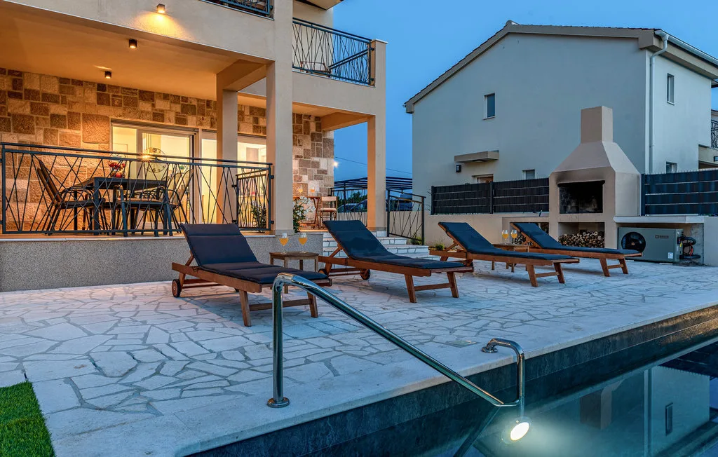 An outdoor poolside patio with lounge seating beside a building.