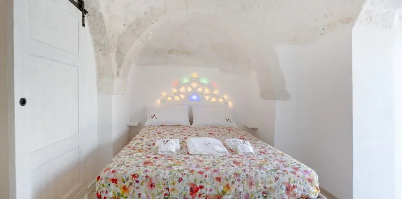 A bedroom with a floral bedspread and colorful light patterns on the wall.
