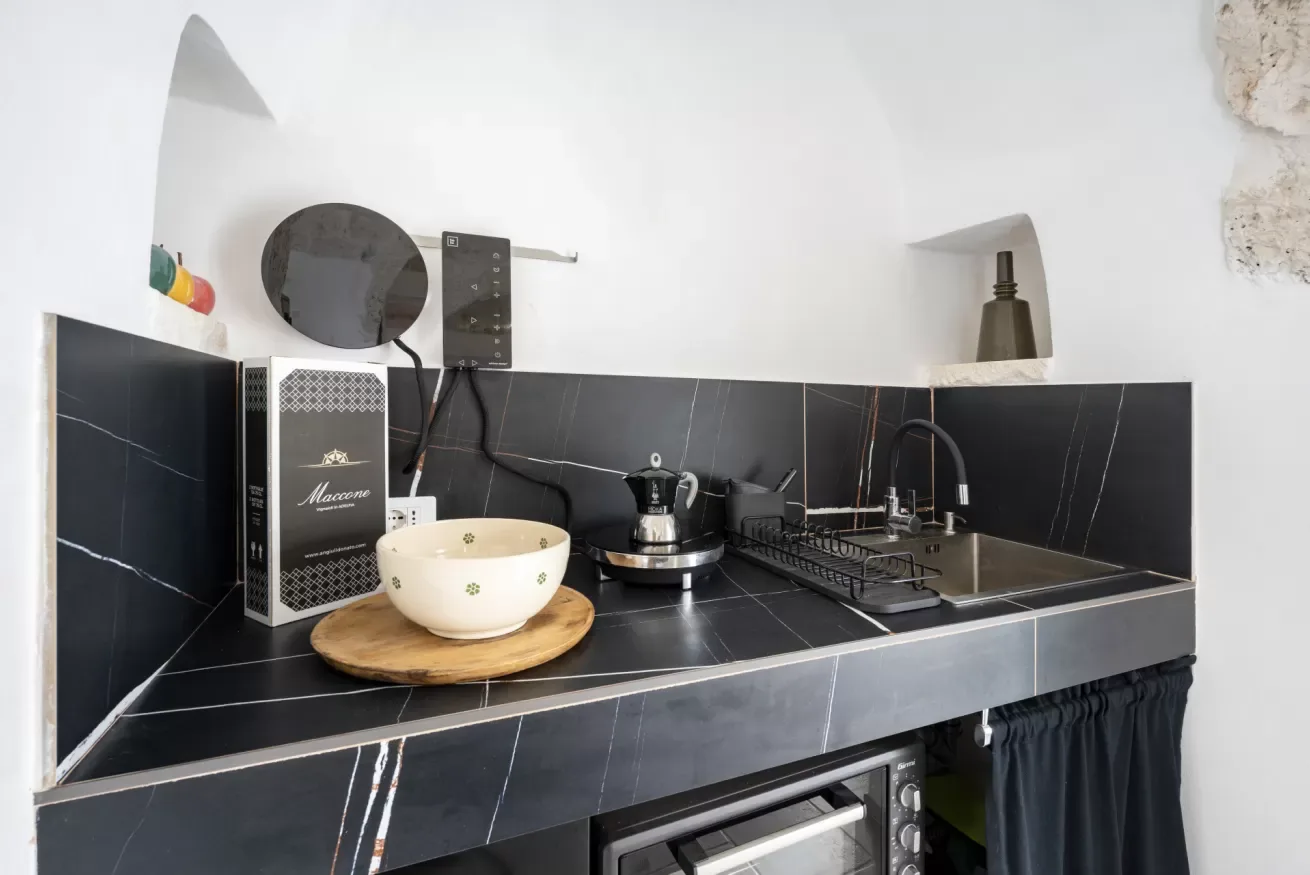 A compact kitchen counter with a sink, stovetop, and small appliances.
