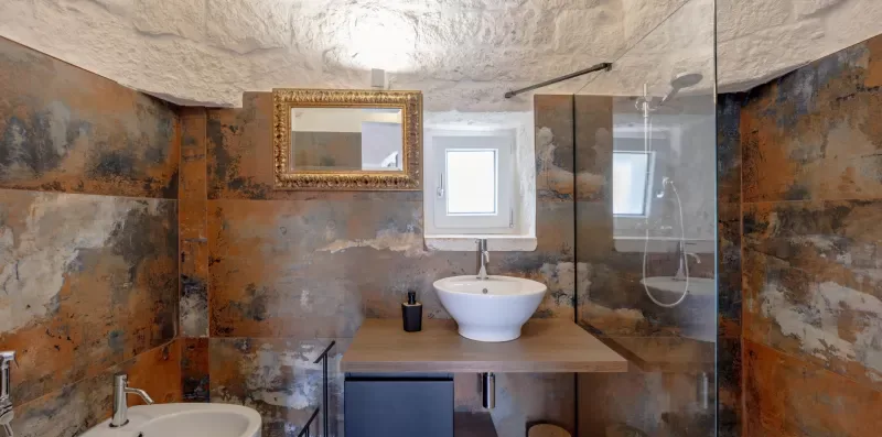 A bathroom with a vessel sink, wall mirror, and glass shower screen.
