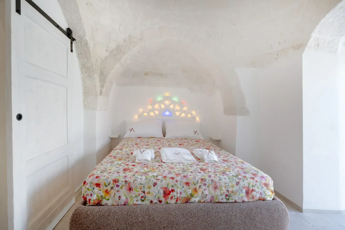 A bedroom with a bed covered in a colorful floral bedspread.