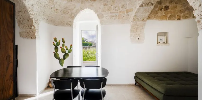 A dining area with a table and chairs beside a low bed.