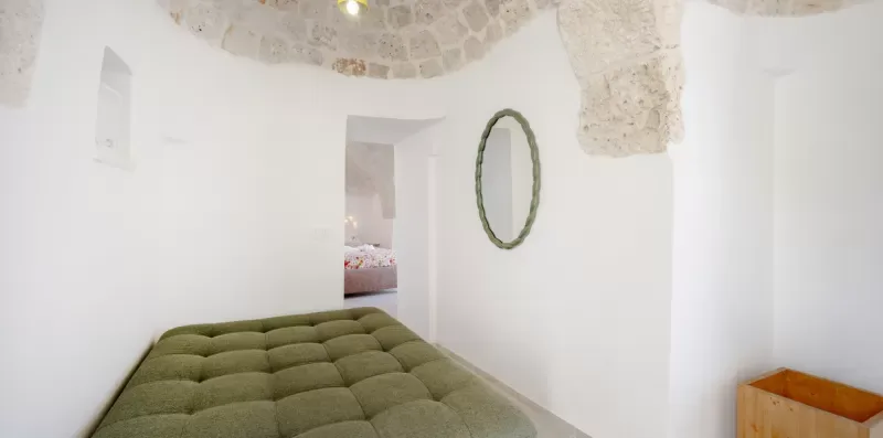 A bedroom with a green bed and an open doorway to another room.