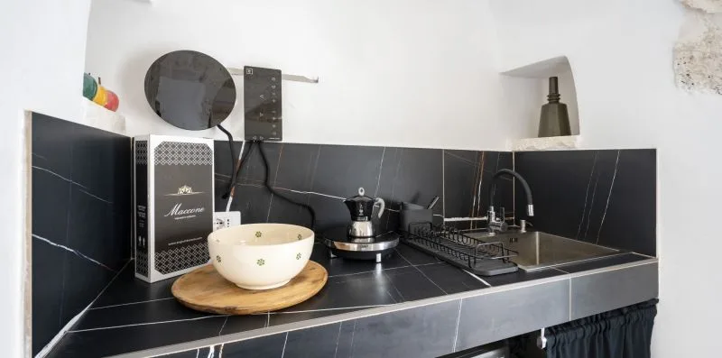 A compact kitchen counter with a sink, cooktop, and small appliances.