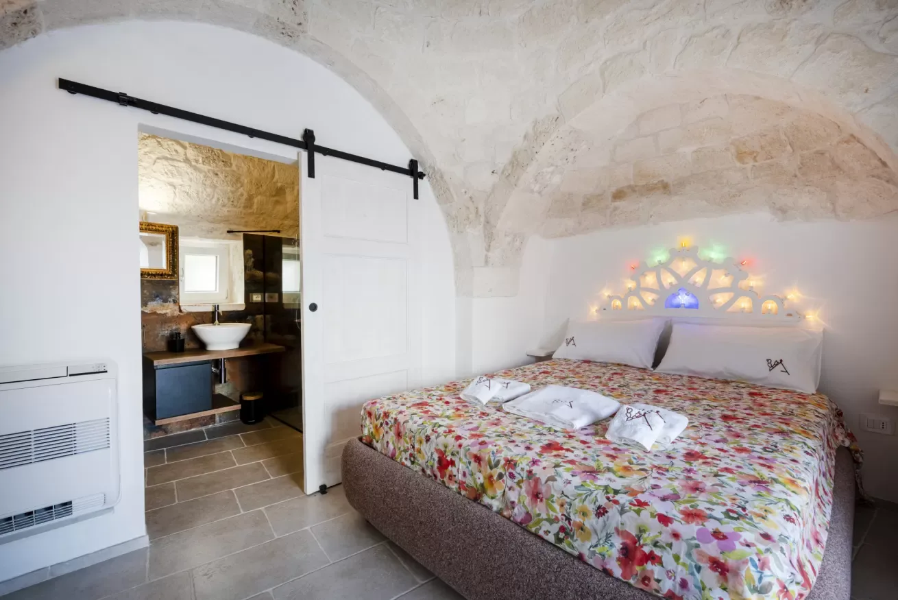 A bedroom with a floral bedspread and an open doorway to a bathroom.