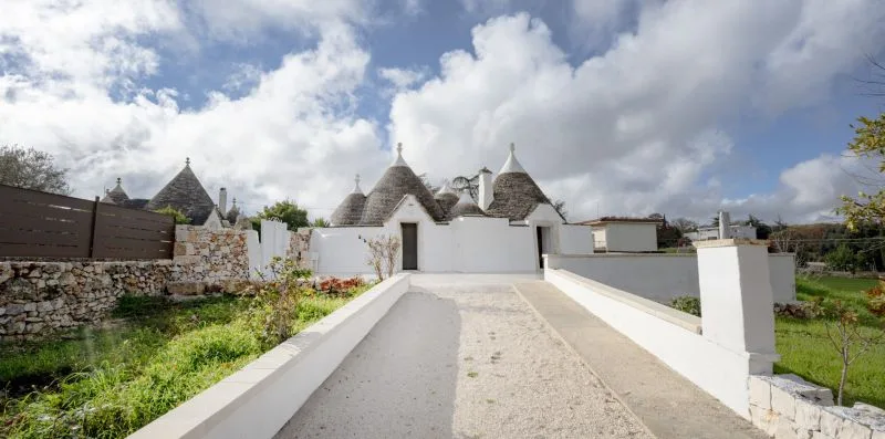 A gravel driveway leads toward white buildings with conical roofs.